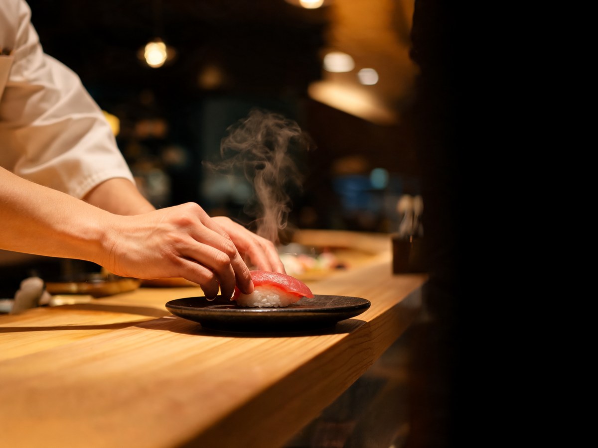 Close-up of a chef's hands pressing a piece of nigiri